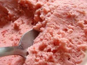 A silver spoon sitting in fresh strawberry ice cream