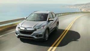 A silver 2023 Honda HR-V driving on a highway by the ocean