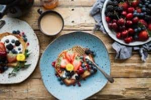 pancakes with fruit on colored plates on a wooden table