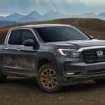 A grey 2023 Honda Ridgeline driving off road with mountains in the background