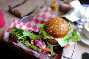 A burger and a side of veggies on a tray