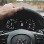 A person holding a black Hyundai steering wheel with one hand