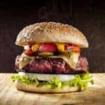 A burger being served on a wooden slab