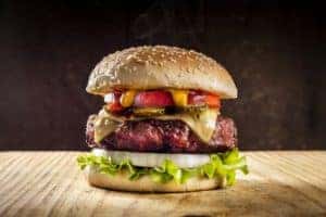 A burger being served on a wooden slab