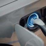 Close up photo of an electric vehicle charger plugged into a silver electric car