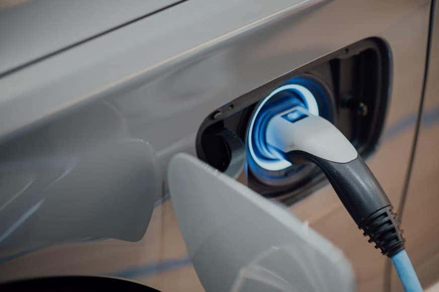 Close up photo of an electric vehicle charger plugged into a silver electric car