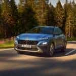 A blue Hyundai Kona driving in a forest setting