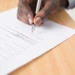 up close image of a person signing a vehicle financing contract
