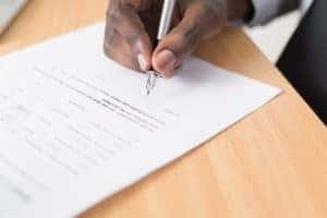 up close image of a person signing a vehicle financing contract