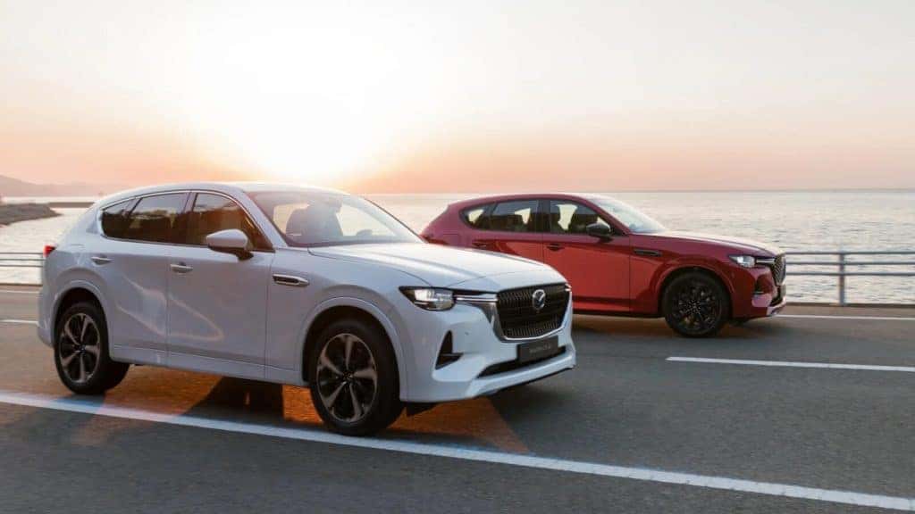 two mazda cx-60 suvs red and white open road sea
