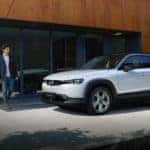 White Mazda MX-30 SUV Man Outside Brown Building