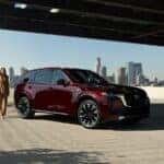 Red Mazda CX-90 SUV Woman Buildings Blue Sky
