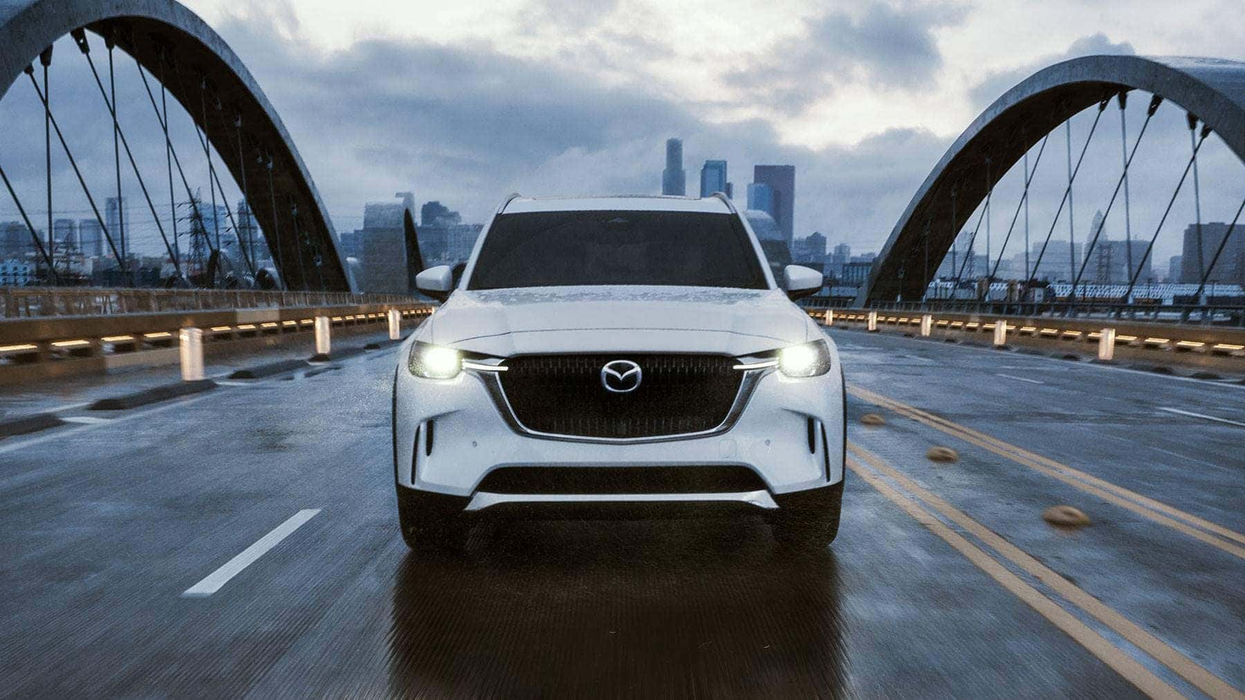 White Mazda CX-90 SUV PHEV Bridge Road Bildings