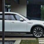 White Mazda CX-90 SUV Two People Trees Water