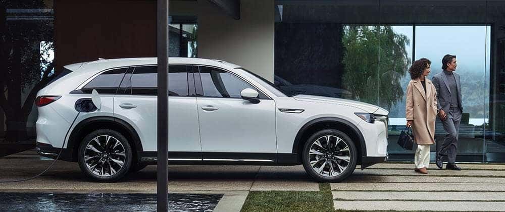 White Mazda CX-90 SUV Two People Trees Water