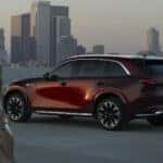 Maroon Mazda CX-90 SUV WOman Buildings