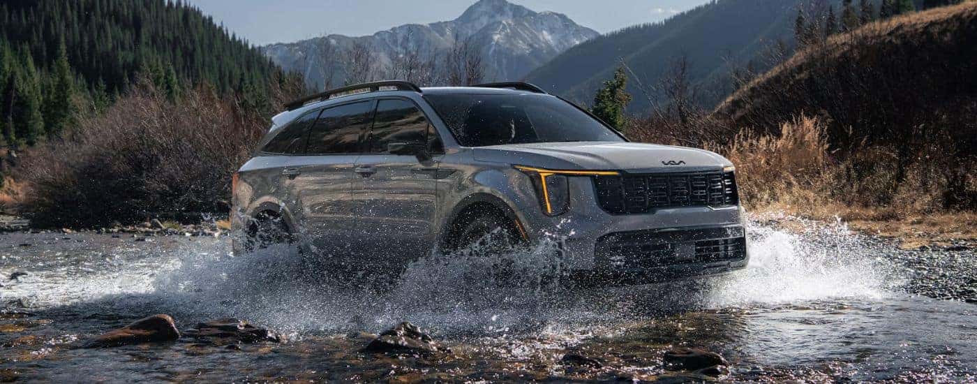 Grey 2026 Kia Sorento driving through a river.