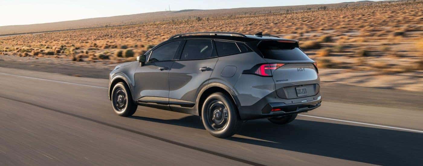 Grey 2026 Kia Sportage rear view driving on a desert road.