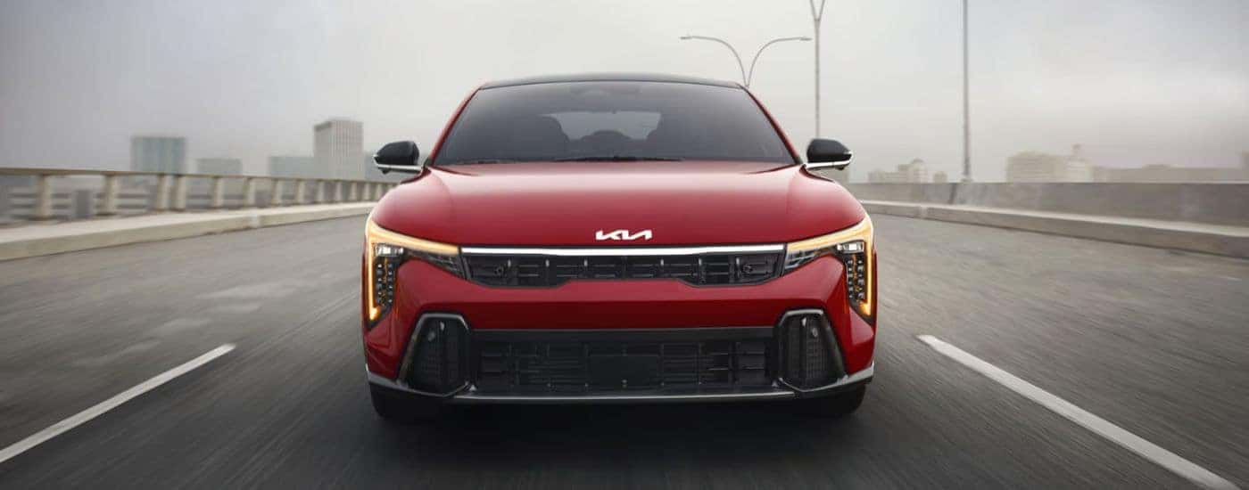 Red 2026 Kia K4 shown from the front with amber daytime running lights.