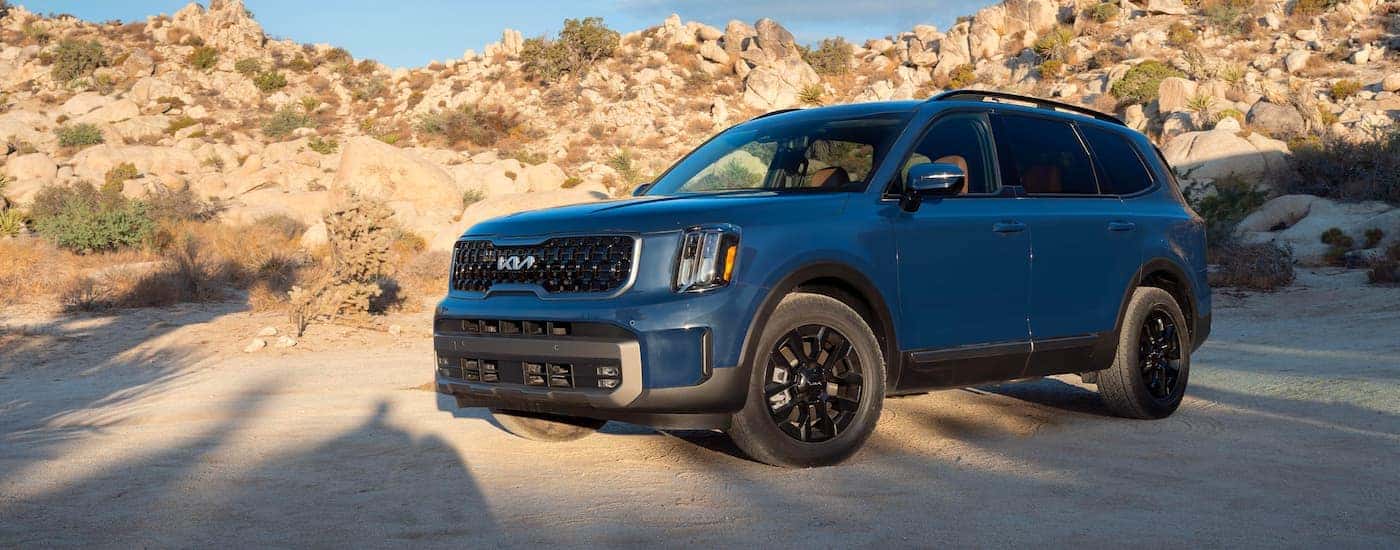 A blue 2023 Kia Telluride parked on sand.