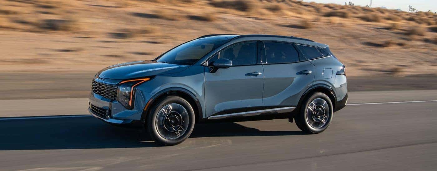 A blue 2026 Kia Sportage Hybrid shown driving a paved road.