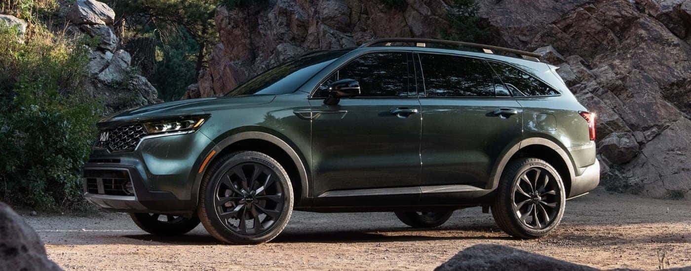 A green 2022 Kia Sorento X-Line parked by a rock wall.