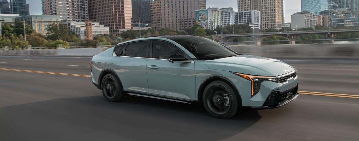 A mint green 2026 Kia K4 GT-Line Turbo shown driving on a city bridge.