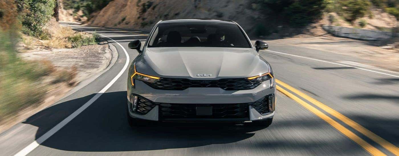 Head-on view of a 2026 Kia K5 GT shown driving a paved road.