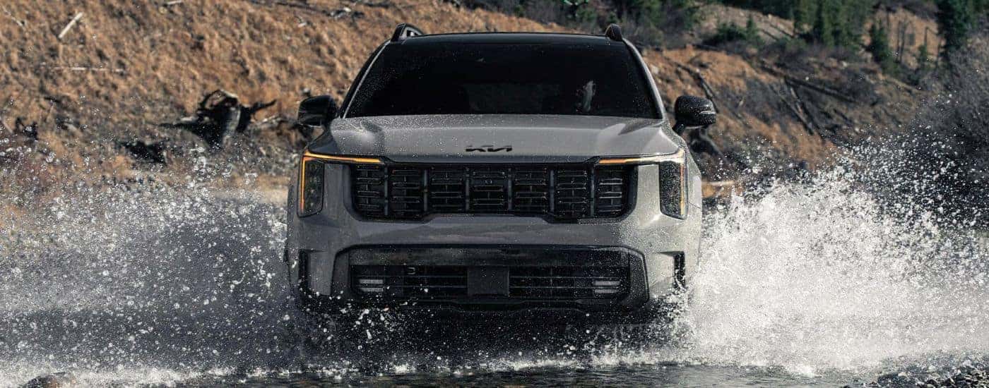 Head-on view of a gray 2026 Kia Sorento X-Pro SX Prestige splashing in water.