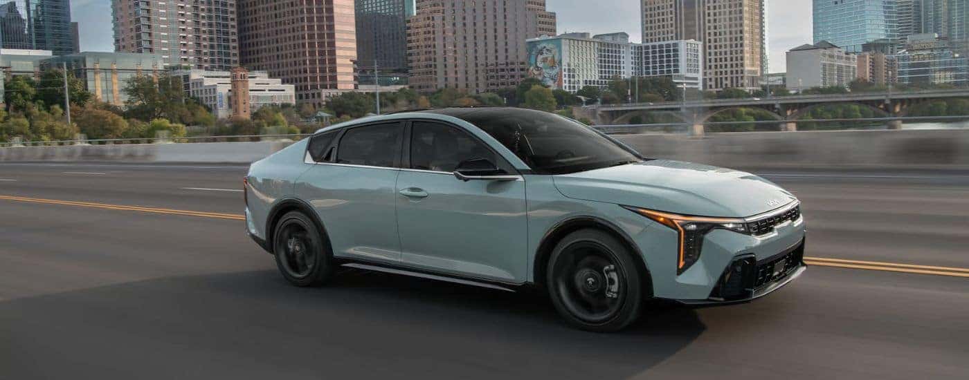 Light blue 2026 Kia K4 GT-Line Turbo driving through a city.