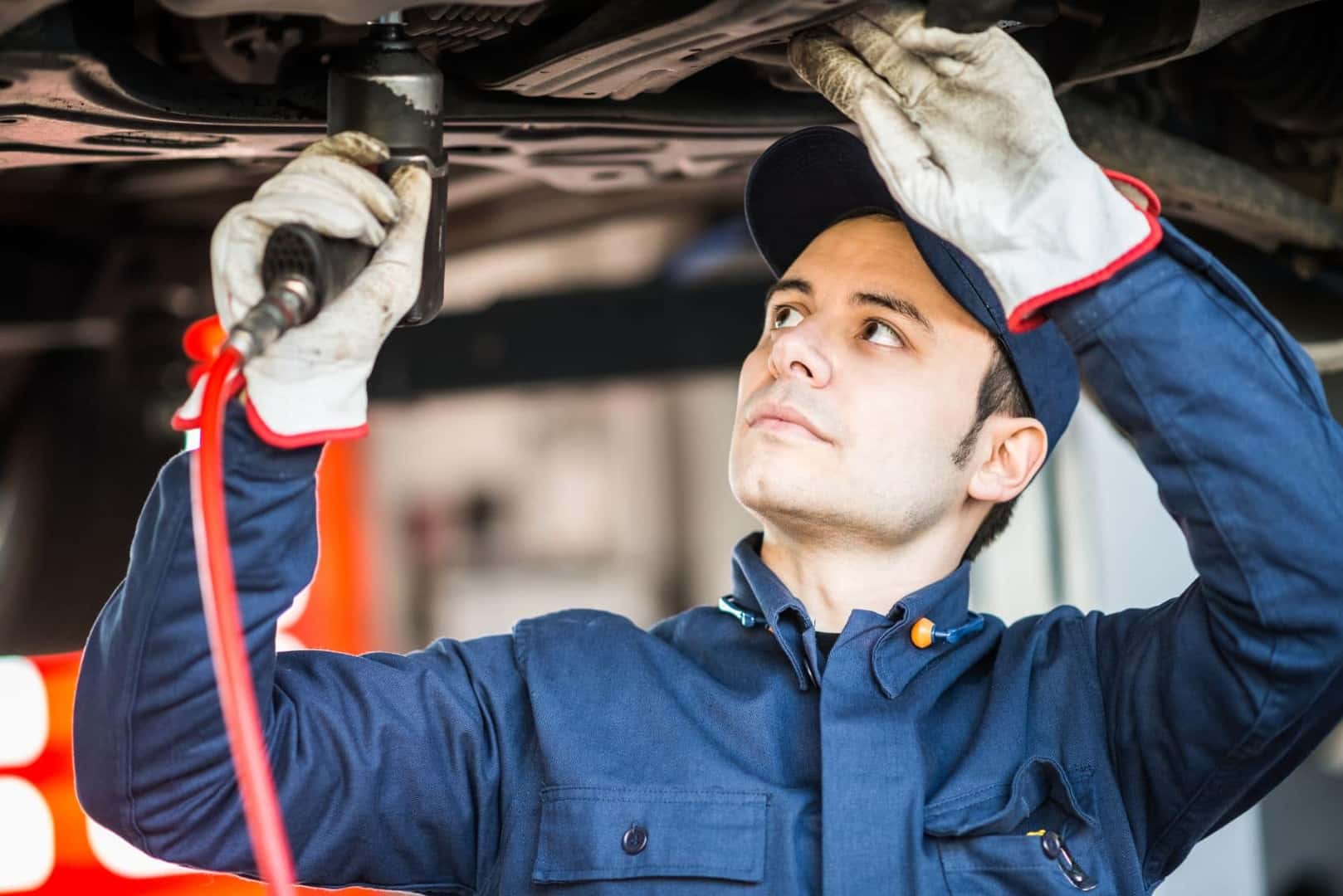 Mechanic using a powertool on the under carriage of a vehicle