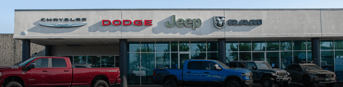 Front of dealership with a Ram 1500 and Jeep Wrangler in front of it.