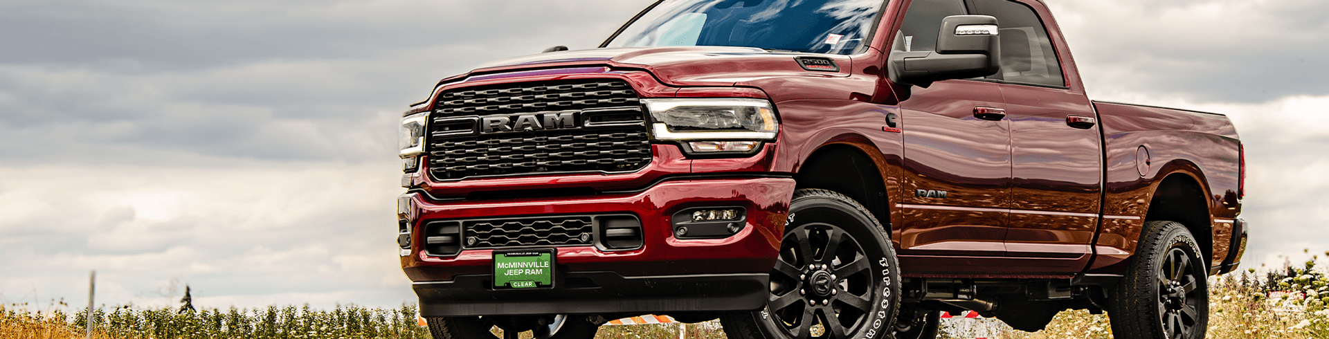 Image of burgundy Ram 1500 on grassy landscape.