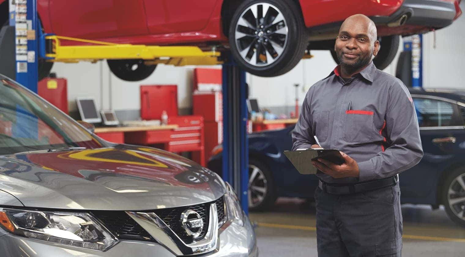 Mechanic standing by silver Nissan SUV