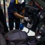 A man cleaning a car with a mask