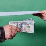 Two people exchanging a piece of paper and money