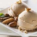 Two scoops of ice cream plated with an assortment of nuts