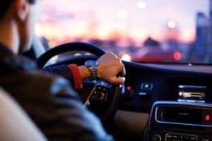 A man wearing a wrist watch driving a car