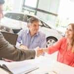 Couple shaking hands on new car deal