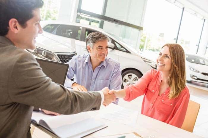 Couple shaking hands on new car deal