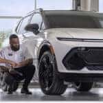 Chevrolet Certified Service technician discussing vehicle maintenance with customers next to a white Chevrolet SUV.