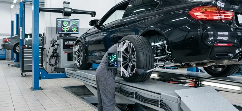 Technician using a Hunter alignment machine to align the wheel of a vehicle raised on a lift