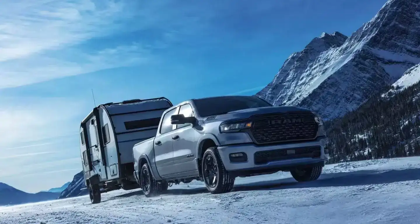 2027 RAM 1500 towing a trailer through snowy mountains
