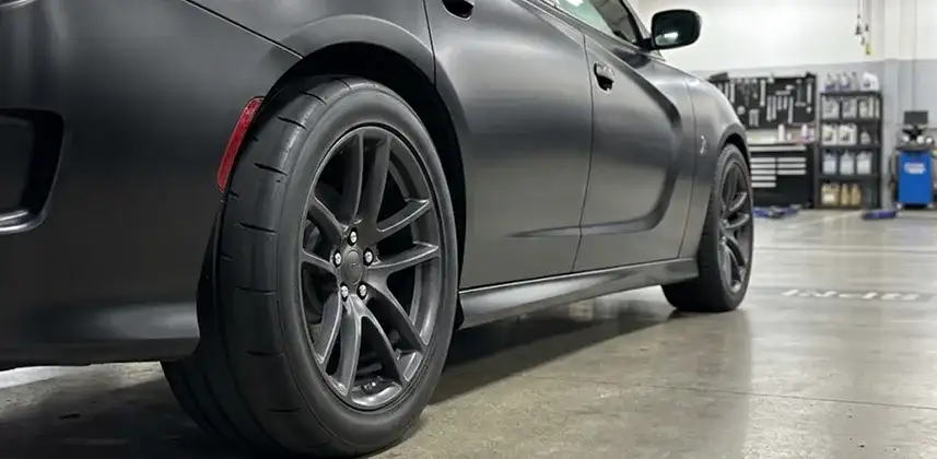 Dark grey Dodge Charger on performance wheels inside the Singing River CDJR shop
