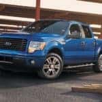 A blue 2014 Ford F-150 STX is shown at a lumber yard.