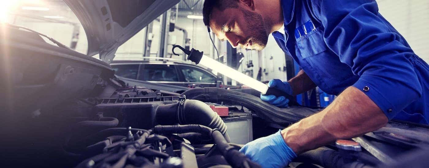 A mechanic is shown with a light doing a multi point inspection at a Certified Pre-Owned Ford dealership.