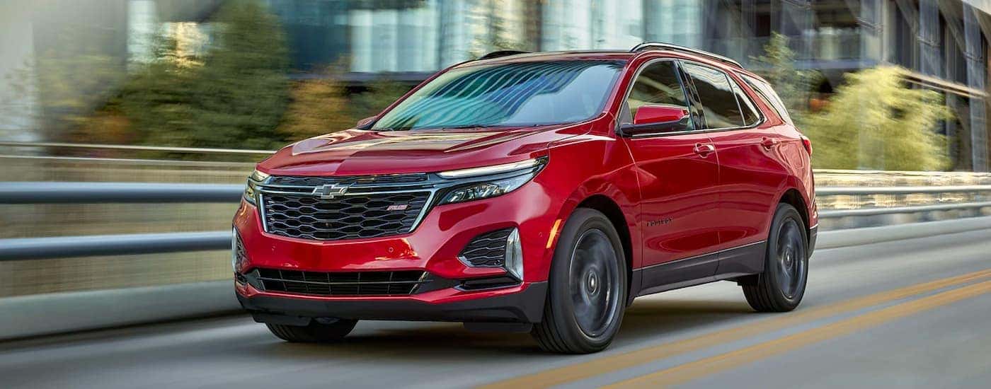 A red 2022 Chevy Equinox RS is shown driving on a city street.