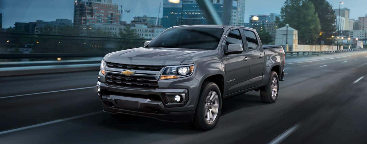 A grey 2022 Chevy Colorado is shown driving over a bridge at night.