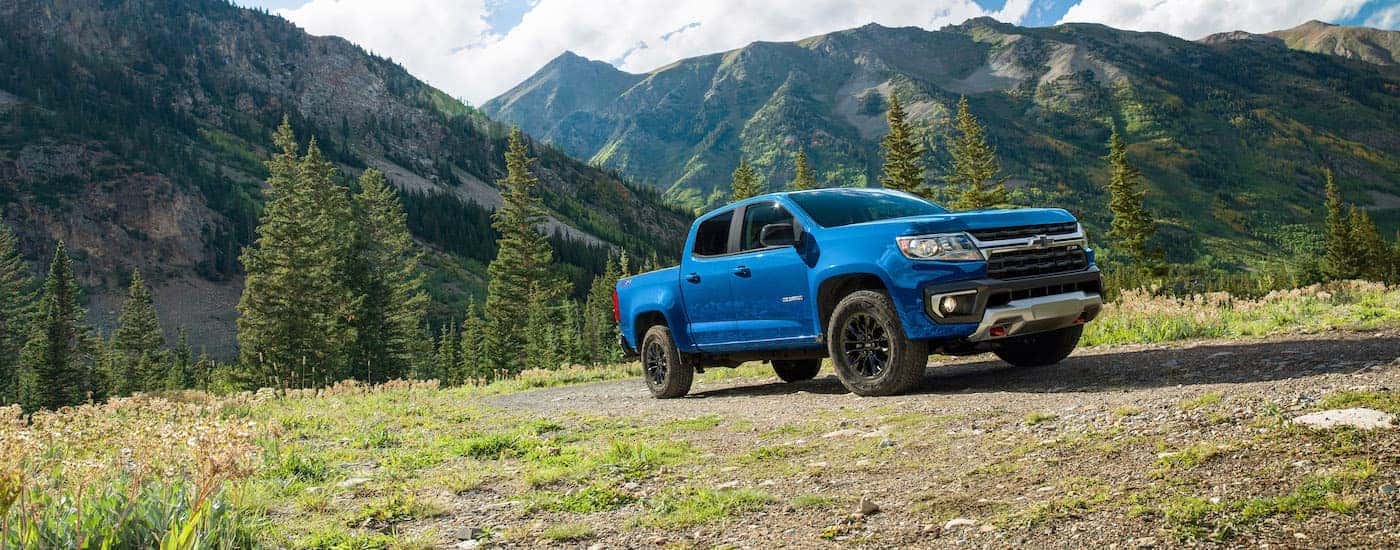 A blue 2022 Chevy Colorado Z71 Trailboss is shown parked in the mountains near evergreen trees.