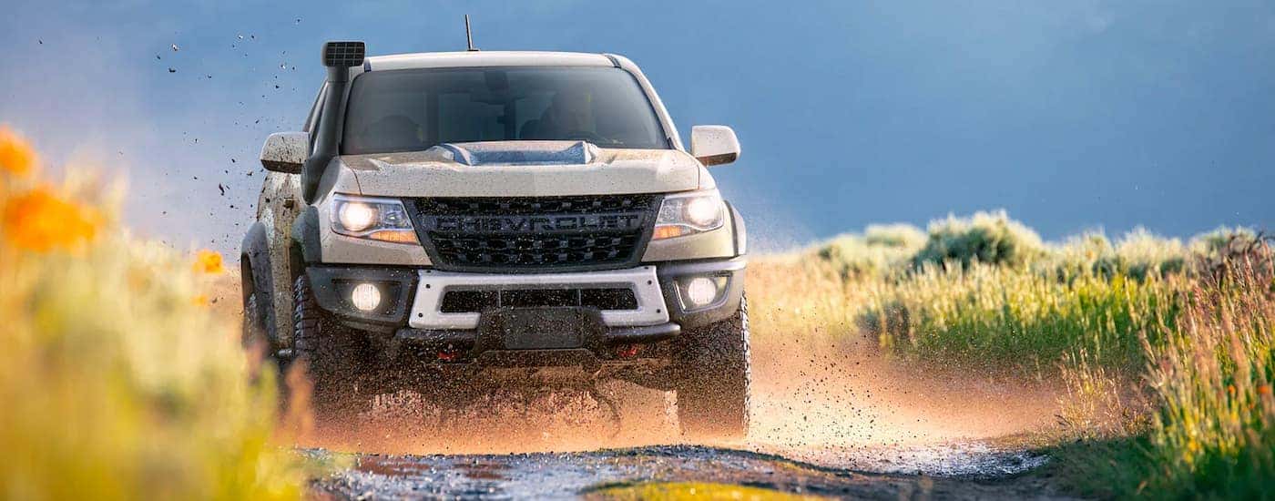 A tan 2022 Chevy Colorado ZR2 Bison is shown driving on a muddy tail.